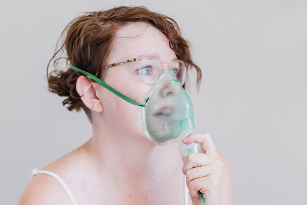Žena sse inhalira z masko za inhalacijo