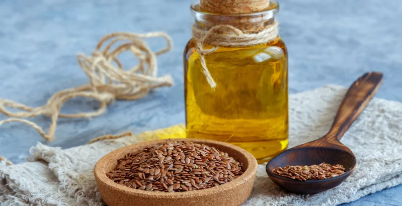 Lanena semena na krožniku in steklenička lanenega olja na mizi