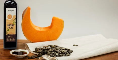 Slika prikazuje oranžno bučo in bučna semena, bučno Nutrigold olje v steklenici