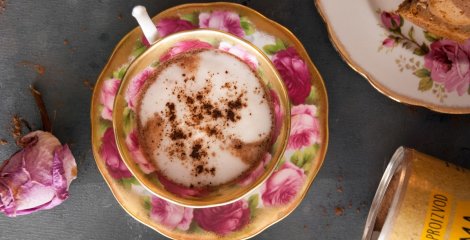 Kremast lucuma kakao latte v skodelii za kavo na črni podlagi.