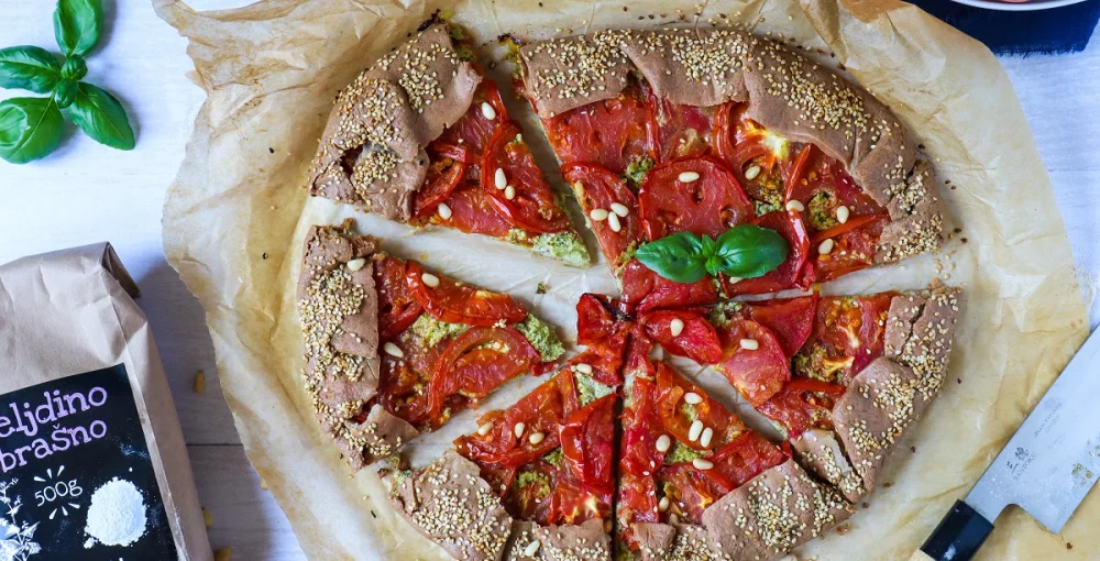 Galette s paradižnikom in baziliko na rjavem papirju.